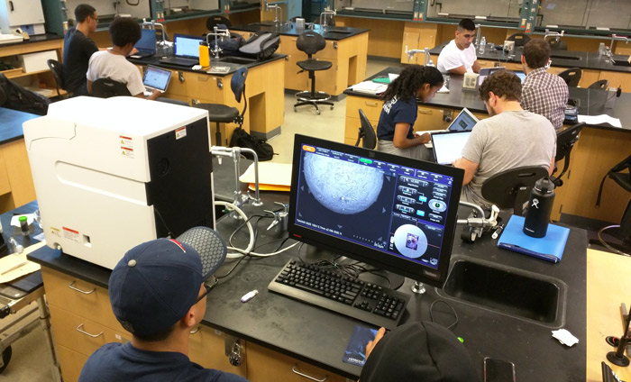 A Nanotechnology student at West Los Angeles College inspecting a sample with an Hitachi SEM.